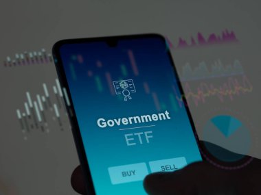 Hükümetin etf fonunu ekranda analiz eden bir yatırımcı. Bir telefon hükümetin fiyatlarını gösterir
