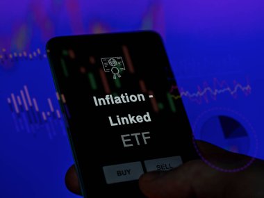 Enflasyonu analiz eden bir yatırımcı. Ekrandaki etf fonu ile bağlantılı. Bir telefon enflasyon fiyatlarını gösterir - bağlantılı