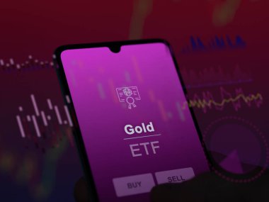 Ekrandaki altın etf fonunu analiz eden bir yatırımcı. Altın fiyatlarını gösteren bir telefon.