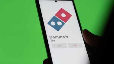April 04th 2024. The logo of Domino's on the screen of an exchange. Domino's price stocks, $DPZ on a device. clipart