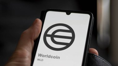 20 Nisan 2024, Şangay, Çin. Değişim ekranındaki Worldcoin 'in logosuna yaklaş. (WLD) Dünya para fiyat hisseleri, bir aygıt WLD $.