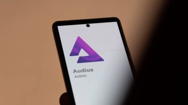Bir takas ekranındaki Audius logosuna (AUDIO) yaklaş. (AUDIO) Audius fiyat hisseleri, bir aygıt üzerinde $AUDIO.