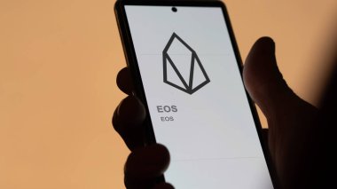 Değişim ekranındaki EOS logosuna (EOS) yaklaş. (EOS) EOS fiyat hisseleri, bir aygıt üzerinde $EOS.