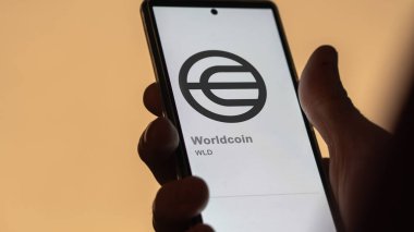 Değişim ekranındaki Worldcoin 'in logosuna yaklaş. (WLD) Dünya para fiyat hisseleri, bir aygıt WLD $.