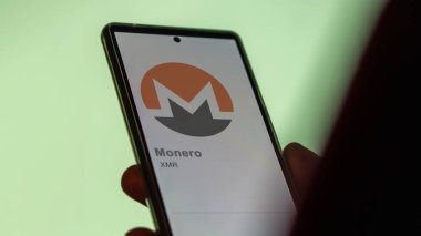 Monero 'nun logosuna bir değiş tokuş ekranında yaklaş. Monero hisse senetleri, cihaza XMR dolar..