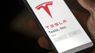 09 Nisan 2024, Austin, Teksas. Tesla A.Ş. 'nin logosuna bir değiş tokuş ekranında yaklaş. Tesla, Inc. Fiyat hisseleri, bir cihaza TSLA $.