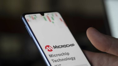 29 Nisan 2024, Chandler, Arizona. Mikroçip Teknolojisi 'nin logosuna bir değiş tokuş ekranında yaklaş. Mikroçip Teknoloji hisse senetleri, bir cihaza $MCHP.
