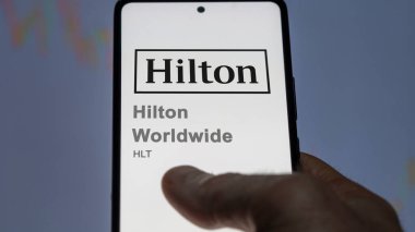 09 Nisan 2024, Tysons Köşesi, Virginia. Hilton Worldwide 'ın logosuna bir değiş tokuş ekranında yaklaş. Hilton dünya çapında hisse senetleri, bir cihaza HLT $.