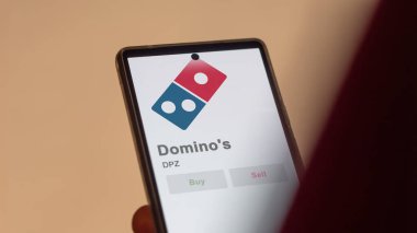 29 Nisan 2024, Ann Arbor, Michigan. Değiş tokuş ekranındaki Domino 'nun logosuna yaklaş. Domino 'nun hisse senetleri, cihaz için DPZ $.