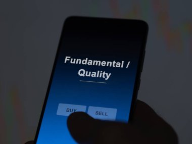 Ekrandaki temel / kaliteli etf fonunu analiz eden bir yatırımcı. Bir telefon Temel / Kalite fiyatlarını gösterir