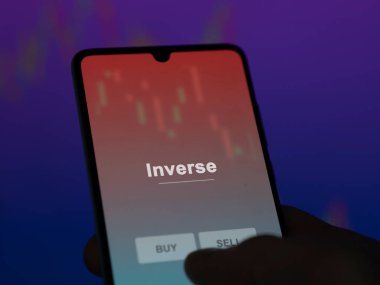 Ekrandaki ters etf fonunu analiz eden bir yatırımcı. Bir telefon ters fiyatları gösterir