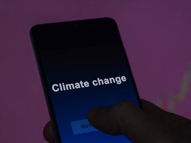 An investor analyzing the climate change etf fund on a screen. A phone shows the prices of Climate change clipart