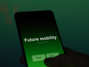 Bir yatırımcı ekranda gelecekteki hareketlilik fonunu analiz ediyor. Bir telefon gelecekteki taşınabilirliğin fiyatlarını gösterir