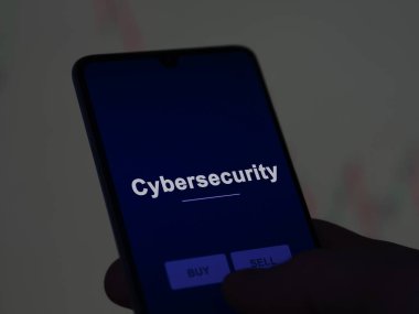 Ekranda siber güvenlik fonunu analiz eden bir yatırımcı. Siber güvenlik fiyatlarını gösteren bir telefon