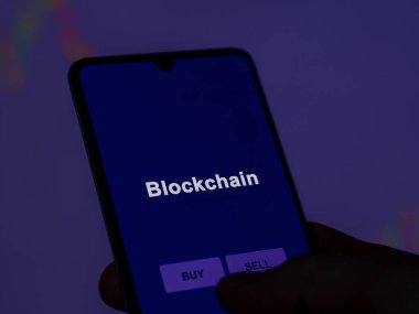 Ekrandaki engelleme fonunu analiz eden bir yatırımcı. Blockchain 'in fiyatlarını gösteren bir telefon