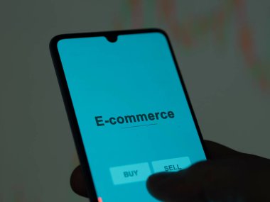 Ekrandaki e-ticaret fonunu analiz eden bir yatırımcı. E-ticaret fiyatlarını gösteren bir telefon