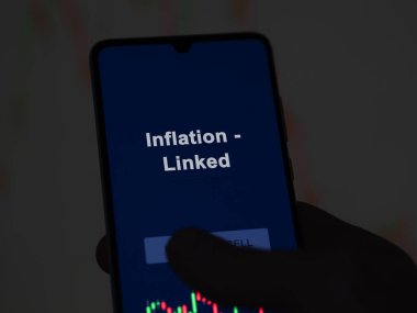 Enflasyonu analiz eden bir yatırımcı. Ekrandaki etf fonu ile bağlantılı. Bir telefon enflasyon fiyatlarını gösterir - bağlantılı