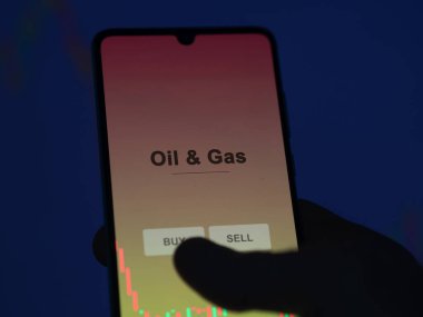 Ekranda petrol ve doğalgaz fonunu analiz eden bir yatırımcı. Bir telefon Petrol & Benzin fiyatlarını gösterir