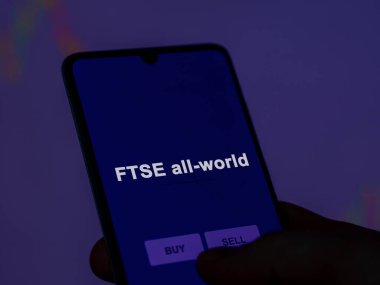 An investor analyzing the ftse all-world etf fund on a screen. A phone shows the prices of FTSE all-world clipart