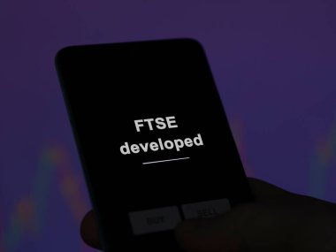 FTse 'yi analiz eden bir yatırımcı ekranda etf fonu geliştirdi. FTSE 'nin geliştirdiği fiyatları gösteren bir telefon.