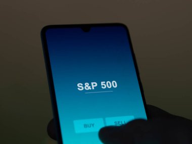 S & p 500 etf fonunu ekranda analiz eden bir yatırımcı. S & P 500 'ün fiyatlarını gösteren bir telefon