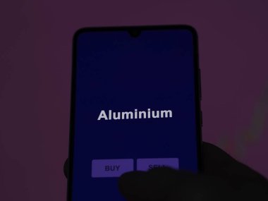 Ekrandaki alüminyum etf fonunu analiz eden bir yatırımcı. Alüminyum fiyatlarını gösteren bir telefon