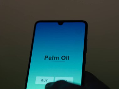 Ekrandaki palmiye yağı fonunu analiz eden bir yatırımcı. Bir telefon Palm Oil 'in fiyatlarını gösterir