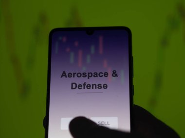 An investor analyzing the aerospace & defense etf fund on a screen. A phone shows the prices of Aerospace & Defense clipart