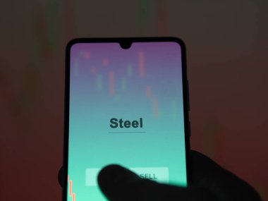 Ekrandaki çelik etf fonunu analiz eden bir yatırımcı. Çelik fiyatlarını gösteren bir telefon.
