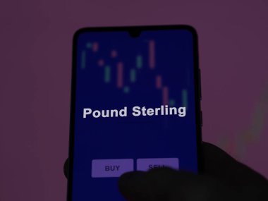 Bir yatırımcı ekrandaki sterling etf fonunu analiz ediyor. Bir telefon Sterling 'in fiyatlarını gösteriyor.