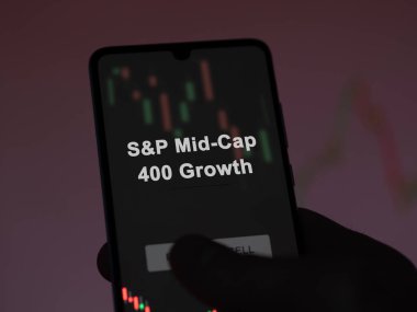 An investor analyzing the s&p mid-cap 400 growth etf fund on a screen. A phone shows the prices of S&P Mid-Cap 400 Growth clipart