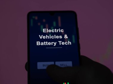 An investor analyzing the electric vehicles & battery tech etf fund on a screen. A phone shows the prices of Electric Vehicles & Battery Tech clipart