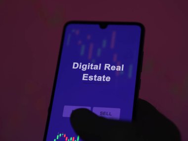 Ekrandaki dijital emlak fonunu analiz eden bir yatırımcı. Dijital Gayrimenkul fiyatlarını gösteren bir telefon