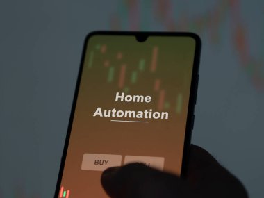 Ekranda ev otomasyon fonunu analiz eden bir yatırımcı. Bir telefon ev otomasyonunun fiyatlarını gösterir