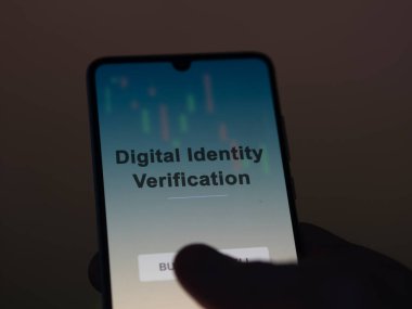 Ekrandaki dijital kimlik doğrulama fonunu analiz eden bir yatırımcı. Dijital Kimlik Doğrulama Fiyatlarını bir telefon gösterir
