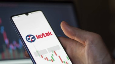 Ekranda Kotak Mahindra Bankası 'nın etf fonunu analiz eden bir yatırımcı. Kotak Mahindra Bankası 'nın fiyatlarını gösteren bir telefon.