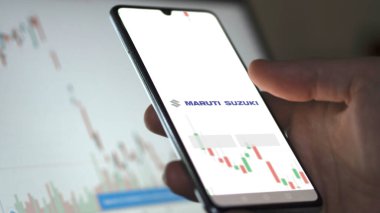 Maruti Suzuki etf fonunu ekranda analiz eden bir yatırımcı. Maruti Suzuki 'nin fiyatlarını gösteren bir telefon.