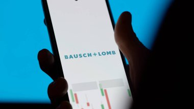 An investor analyzing the bausch & lomb etf fund on a screen. A phone shows the prices of Bausch & Lomb clipart