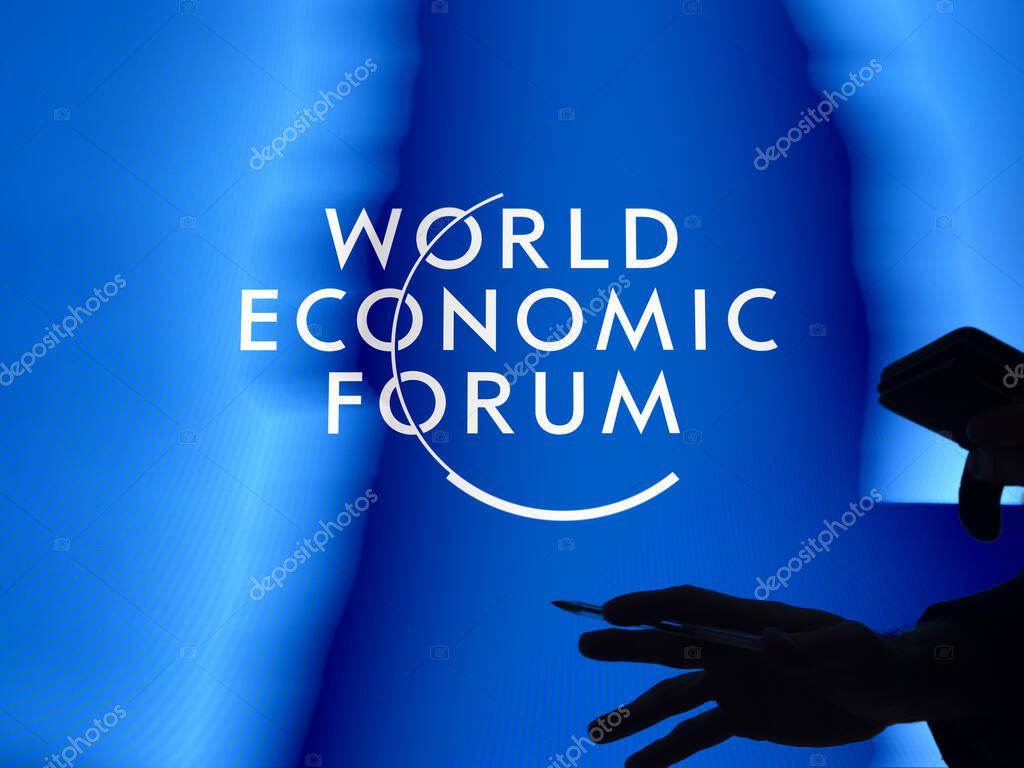 Davos World Economic Forum logo on a window. Passer-by slhouette in the foreground