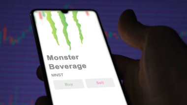 Corona, Kaliforniya. Değiş tokuş ekranındaki Canavar İçeceği logosuna yaklaş. Canavar Meşrubat fiyatları hisse senetleri, bir cihazda MNST $.