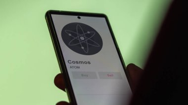 Bir değiş tokuş ekranındaki ATOM kozmos kripto varlığının logosuna yaklaş. ATOM Cosmos hisse senedi fiyatları, bir cihazın atomları..