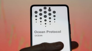 Bir değiş tokuş ekranındaki OCEAN Okyanus Protokolü kripto varlığının logosuna yaklaş. OCEAN Okyanus Protokolü hisse senetleri, bir aygıt üzerinde $OCEAN.