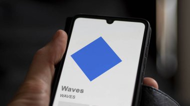Bir değiş tokuş ekranındaki WAVES dalgalarının kripto varlığının logosuna yaklaş. Dalgalar fiyat hisselerini dalgalandırır, cihaz için $WavES.