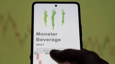 Corona, Kaliforniya. Değiş tokuş ekranındaki Canavar İçeceği logosuna yaklaş. Canavar Meşrubat fiyatları hisse senetleri, bir cihazda MNST $.