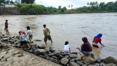 Pinrang Endonezya, 12 Temmuz 2023: Pinrang Fort 'ta yaşayan binlerce kişi, baraj kapısı sabah temizlenmek üzere açıldığında balık ve karides yakalamakla meşguller.