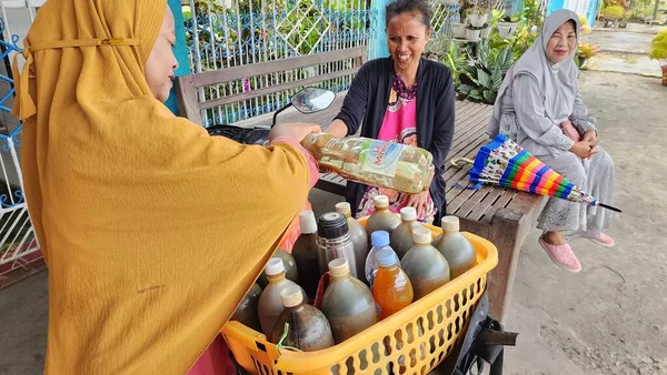 pinrang Indonesia, 21 July 2023: A female herbal medicine seller, serving customers in front of the house in the morning in the village of Masolo Pinrang, Indonesia