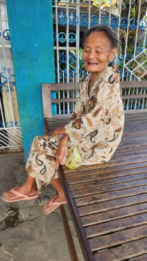 Pinrang Endonezya 28 Temmuz 2023: Yaşlı bir anne, Masolo Pinrang Endonezya köyünde sağlıklı ve mutlu bir gülümsemeyle salonda rahat bir şekilde oturuyor.