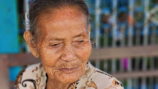 Pinrang Endonezya, 28 Temmuz 2023: Masolo Pinrang Endonezya köyünde sabah yaşlı bir anne kameraya poz verirken şaşkın ve şaşkın bir yüzle salonda oturuyor.