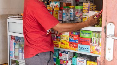 Pinrang Endonezya 30 Eylül 2023: Endonezya 'nın Pinrang şehrinde bir eczaneden tablet ilaç alan Asyalı bir adamın portresi