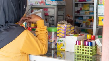 Pinrang Endonezya 30 Eylül 2023: Endonezya, Endonezya 'da sabah saatlerinde bir eczaneden tablet ilaç alan Asyalı bir kadının portresi 